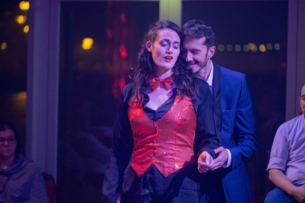 Alfredo steht hinter Violetta und hält ihre Hand