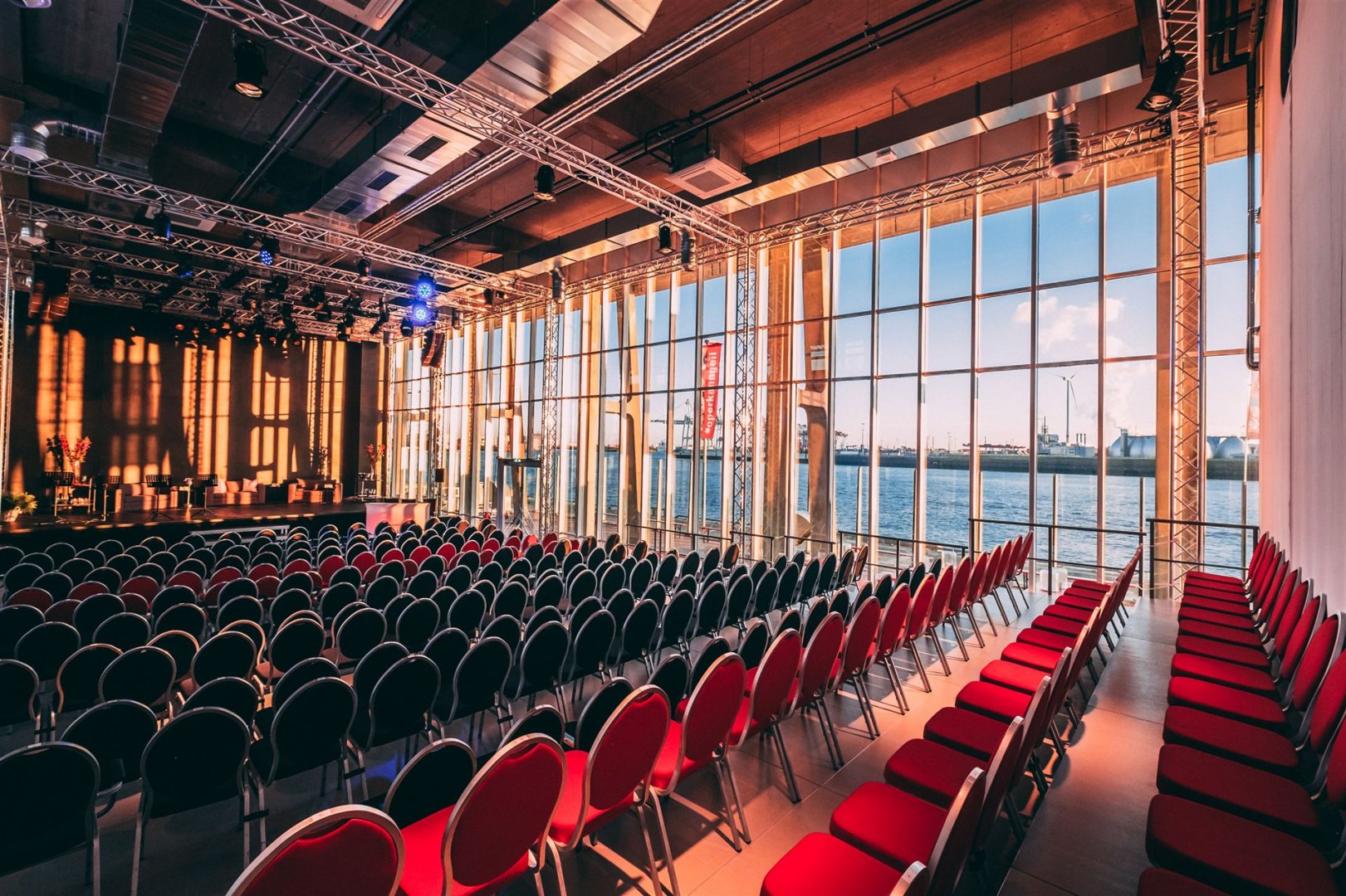 Saal des Opernlofts mit Reihenbestuhlung und großer Fensterfront mit Blick auf das Wasser