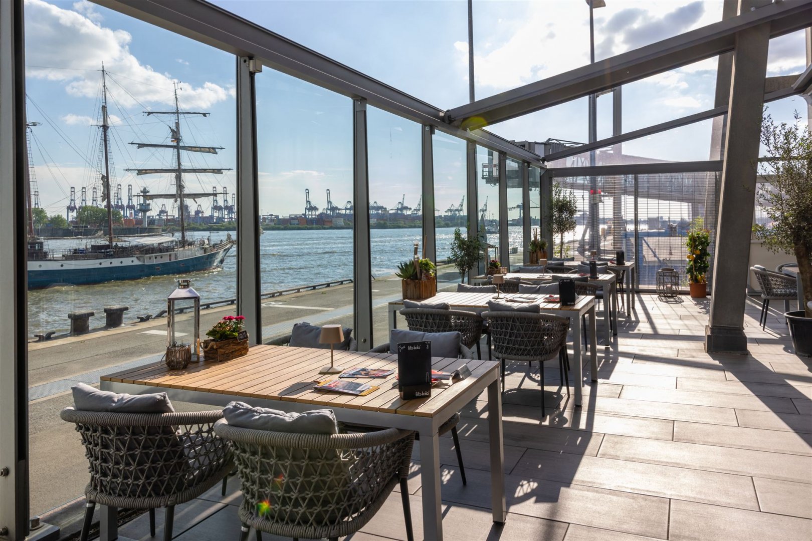Tische auf der Terrasse, die Sonne scheint durch das geöffnete Schiebedach